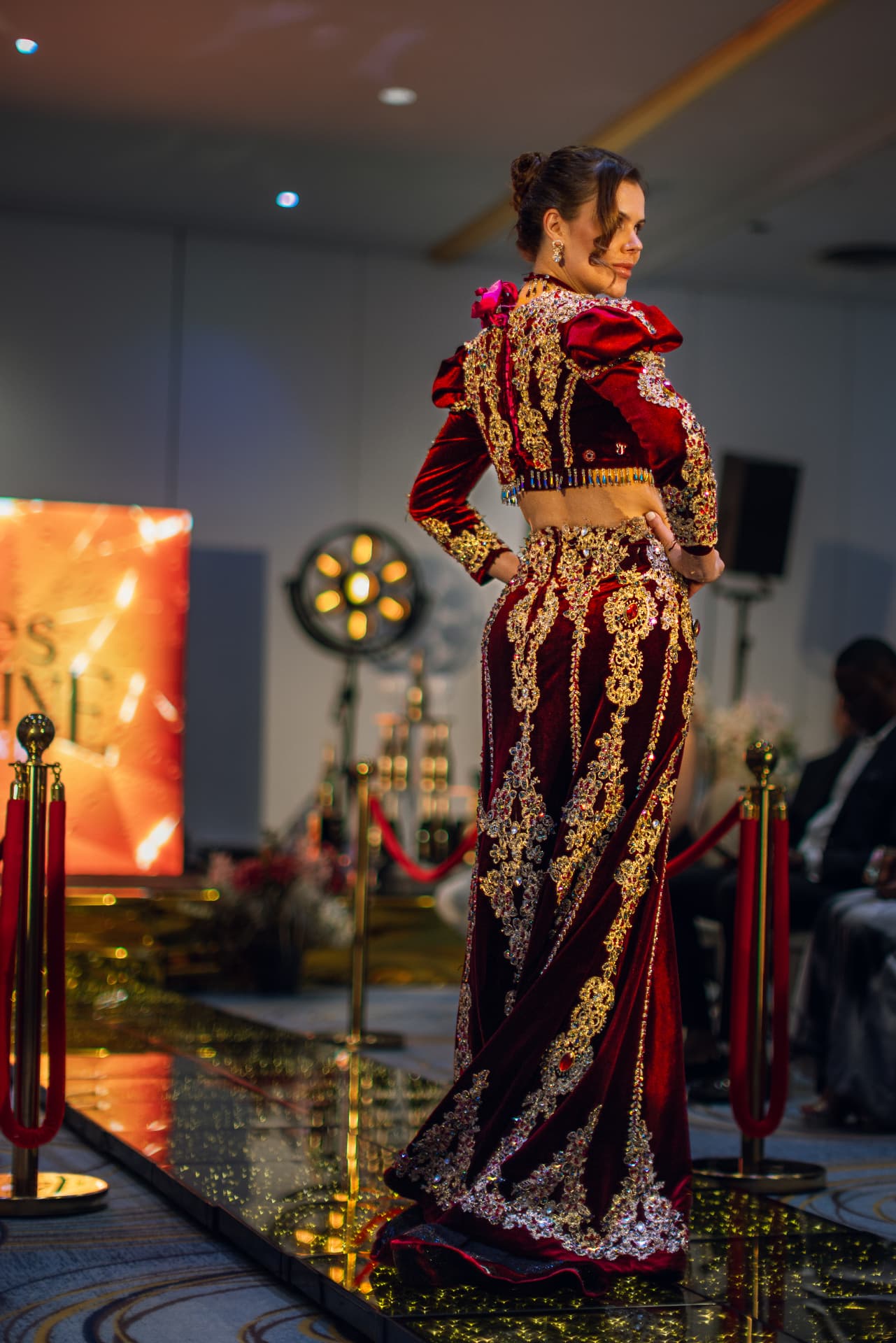 Model in a red velvet and gold gown on the Summit runway