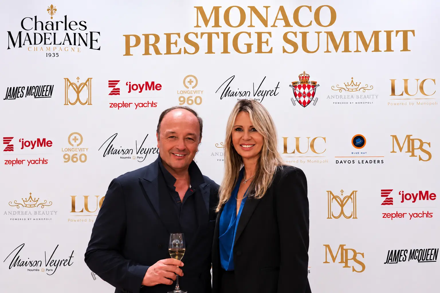 Guests with champagne at the Monaco Prestige Summit media wall